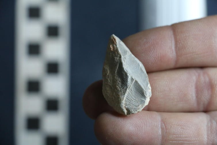 A hand holding a small stone tool.