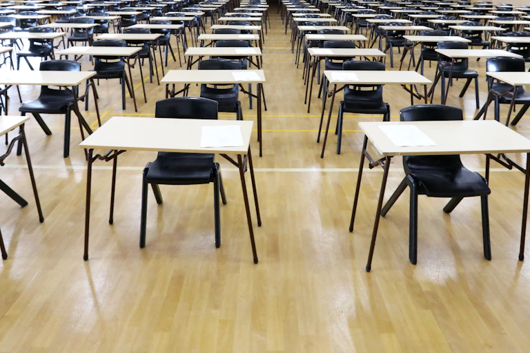 A large exam hall with desks and empty chairs