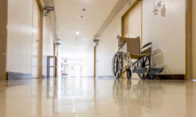 An empty wheelchair sits in the hallway of an aged care facility.