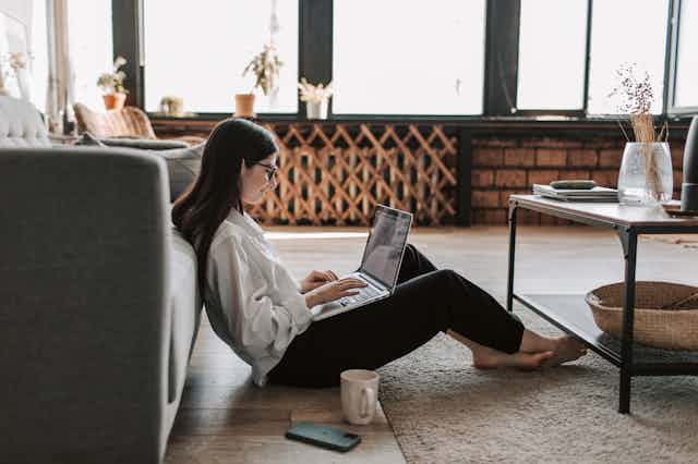 woman working at home sitting on the floor with with her laptop