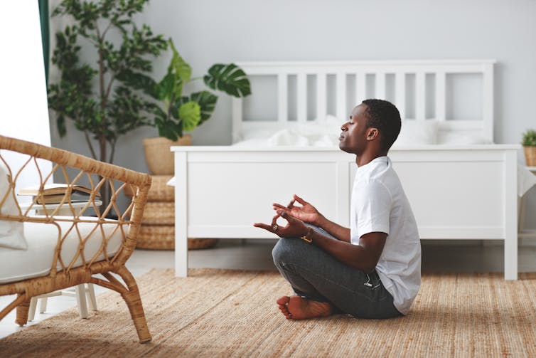 Young Black man sitting cross-legged, meditating.