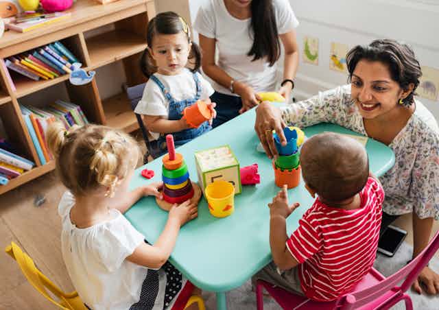 nursery teachers with three children at table