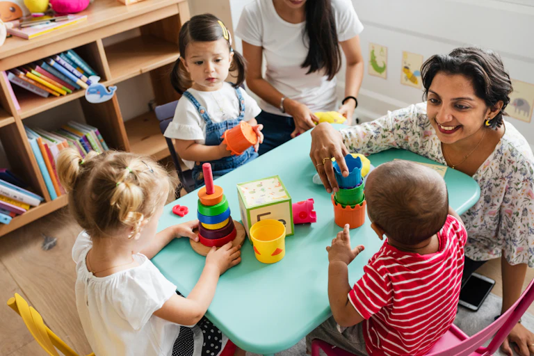 nursery teachers with three children at table