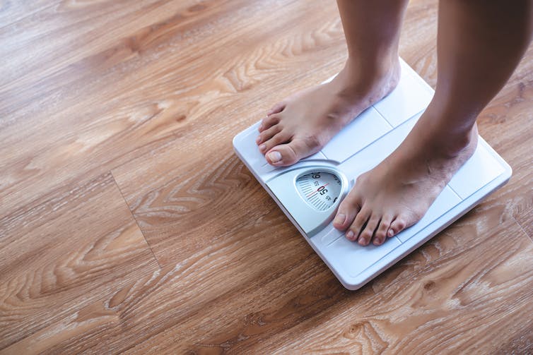 'Person stands on white bathroom scale'