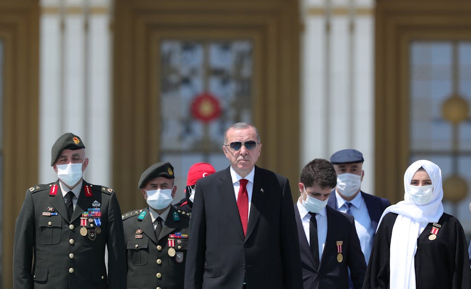 Recep Tayyip Erdoğan walking with group of people two in military uniform