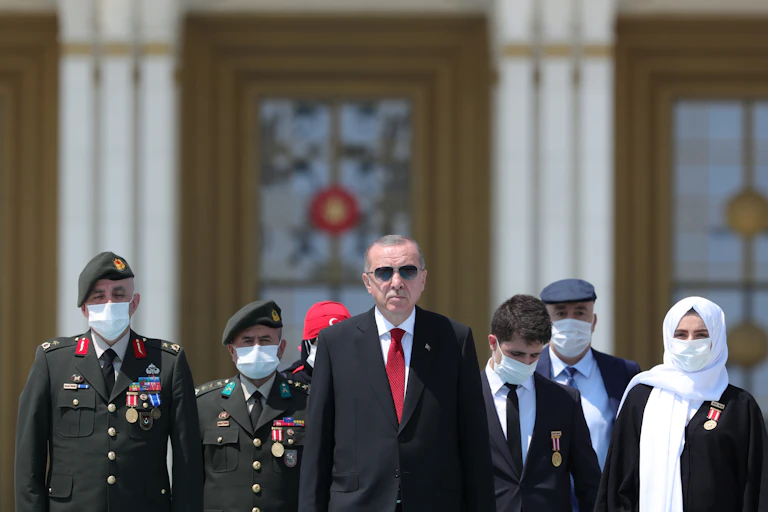 Recep Tayyip Erdoğan walking with group of people two in military uniform