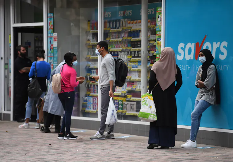 People social distance in a queue outside a UK shop