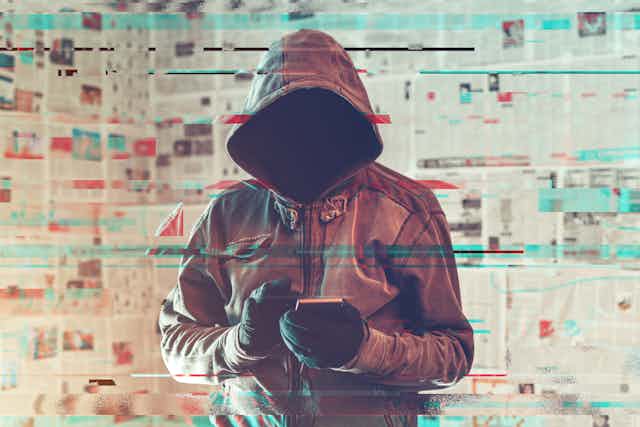 hooded figure holding smart phone