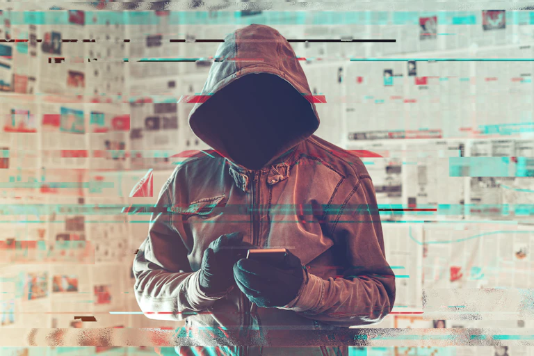 hooded figure holding smart phone