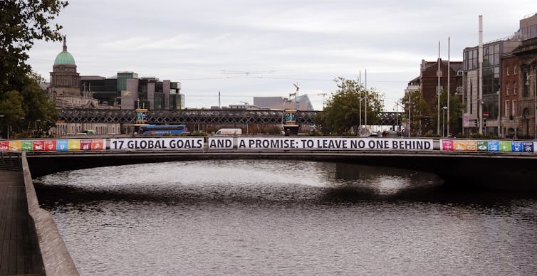 A banner promoting the UN Sustainable Development Goals hangs along the span of a bridge.