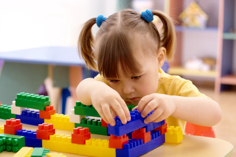 Preschool-age girl playing with plastic building bricks.