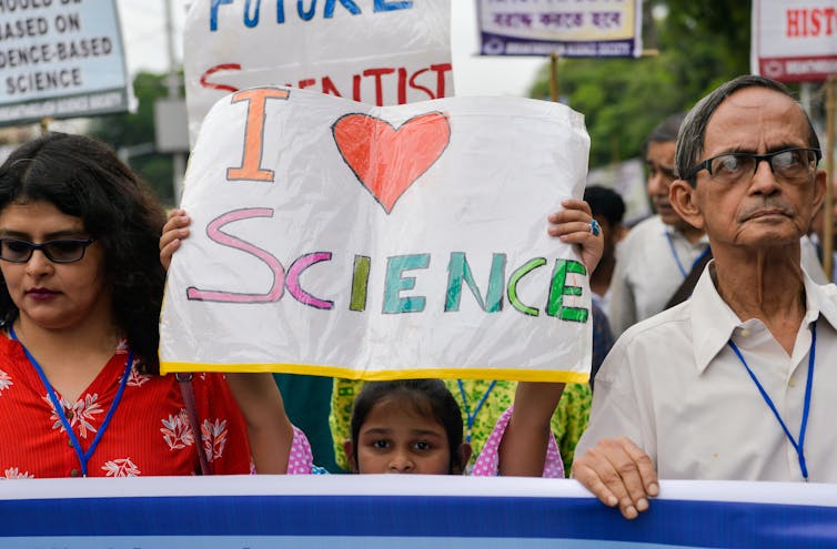 Girl holds up an 'I heart science' sign at a march