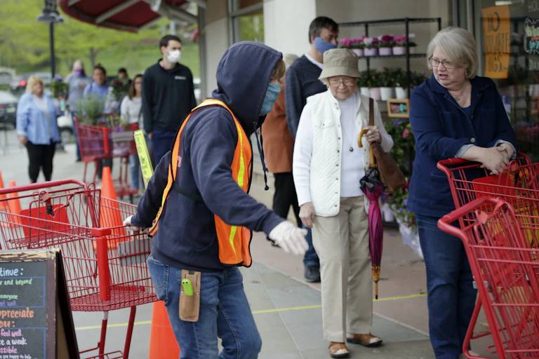 Doorman Dilon Moore, center, helps with shopping carts and controls the number of customers allowed to shop at one time at a Trader Joe's supermarket in Omaha, Neb., on May 7.