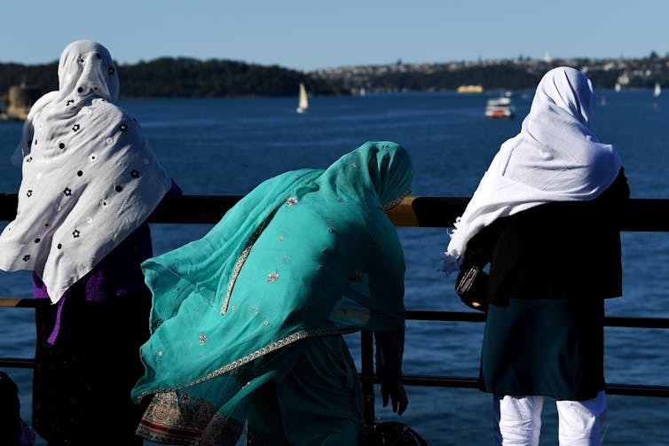 Three Muslim women standing next to a harbour.