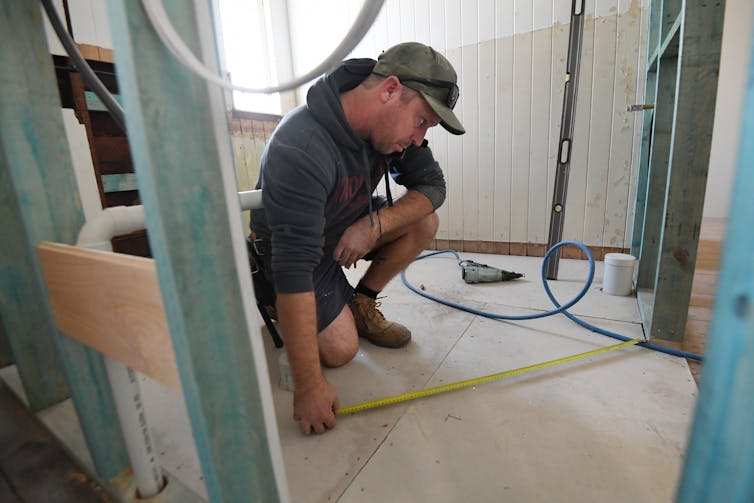 A builder measures a room for a home being renovated.