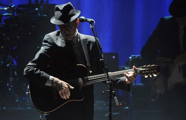 Singer Leonard Cohen in black hat onstage.