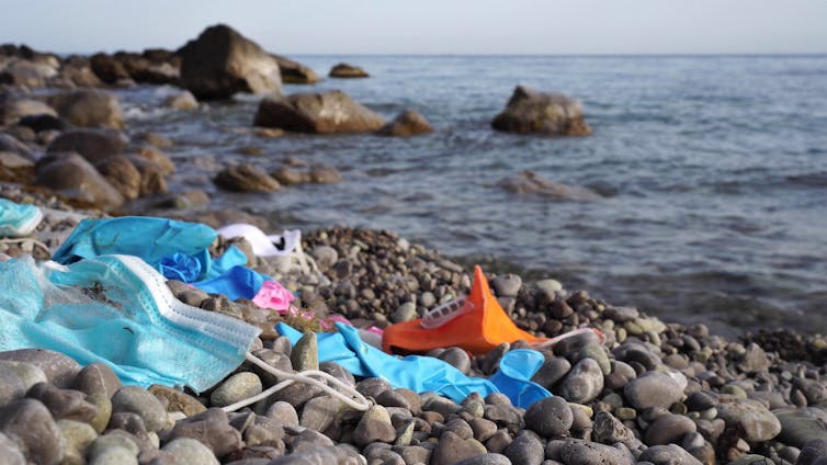Discarded face masks on a rocky beach.