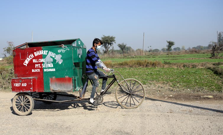 A man in India peddles a bicycle cart to collect rubbish.