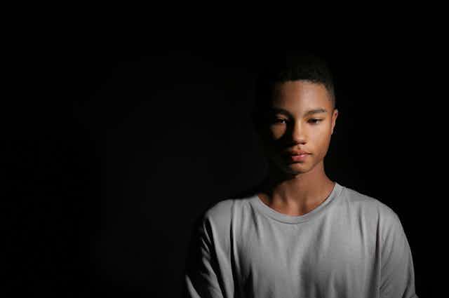 Black teenage boy against black background