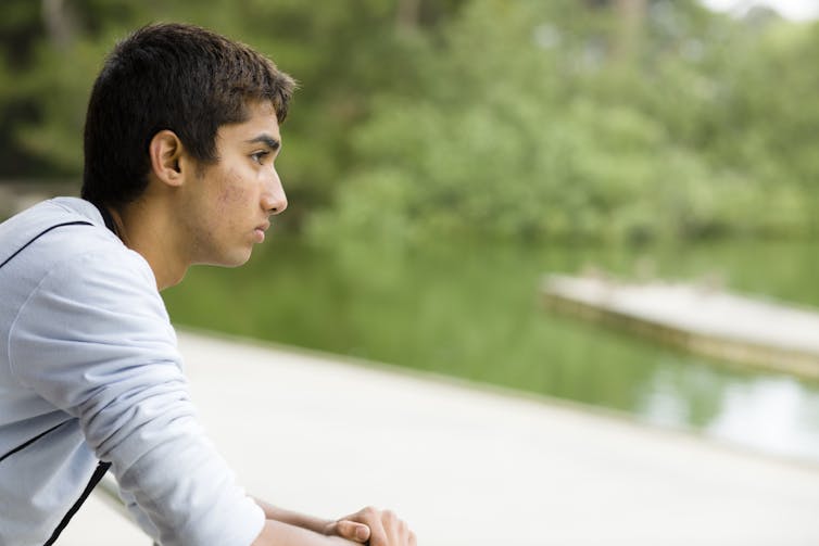 South asian teenage boy looking over lake