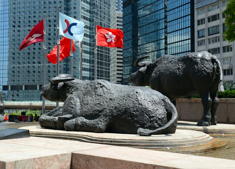 Statue of bull with flags and buildings behind