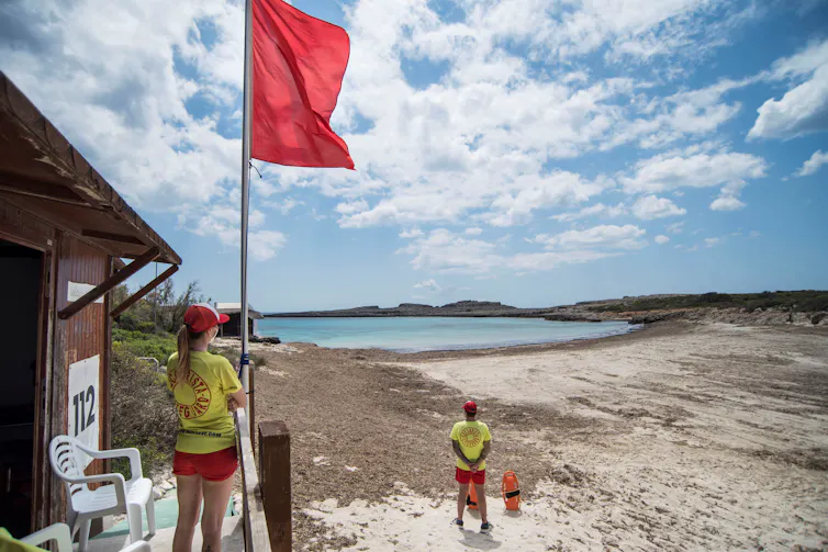 Two lifeguards watch over empty beach.