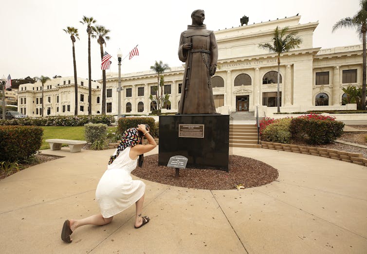 A woman photographing JunÃ­pero Serra statue