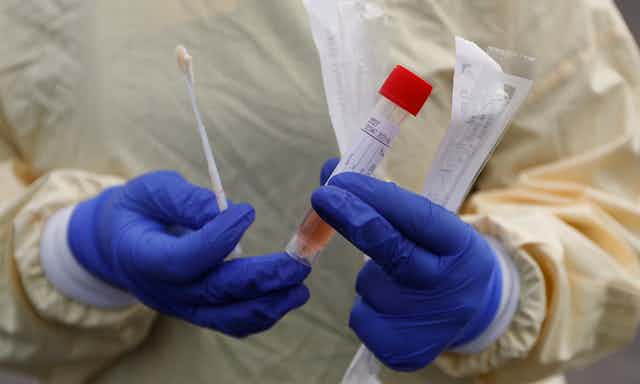 A nurse holding a swab and test tube at a testing station in Michigan