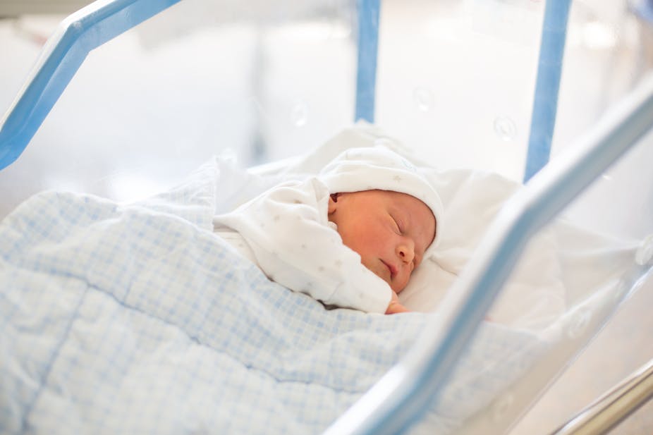 Newborn baby sleeps in a hospital crib