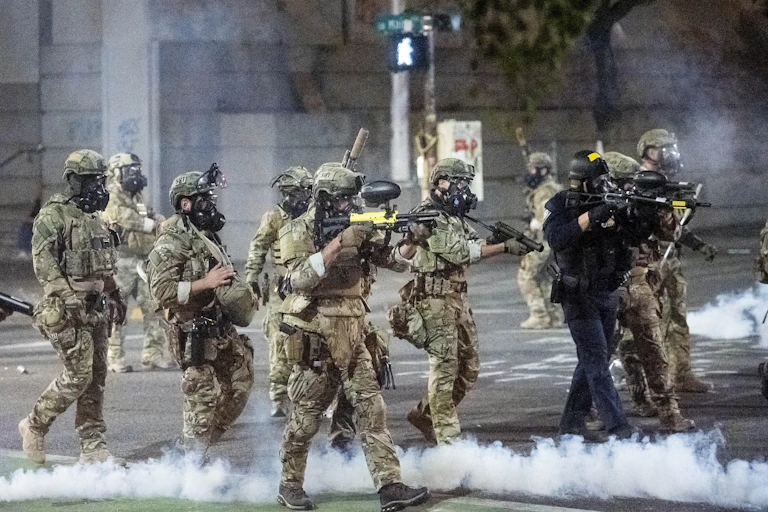 Camouflage-wearing federal officers advance on protesters.