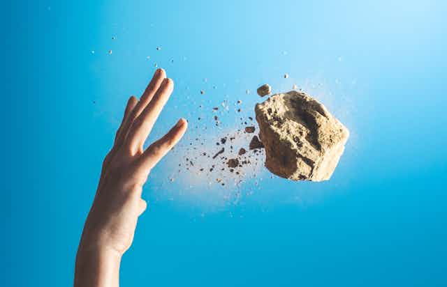A hand throwing a block of concrete