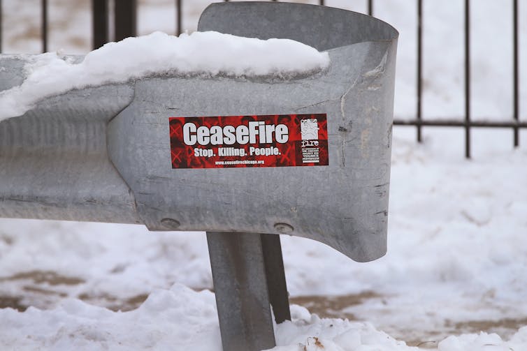 Red bumper sticker on a snow-covered guardrail