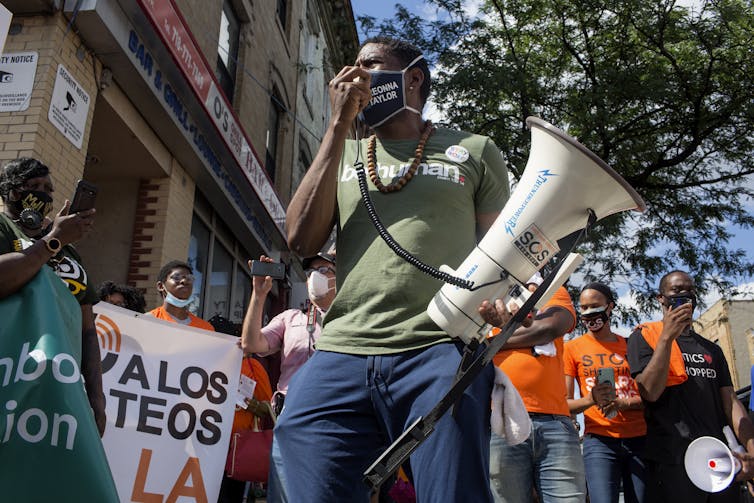 Man speaks on megaphone in front of crowd