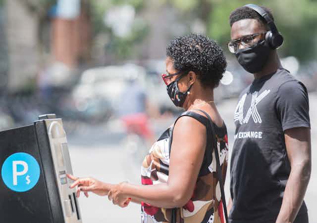 Two people wear face masks as they pay for parking