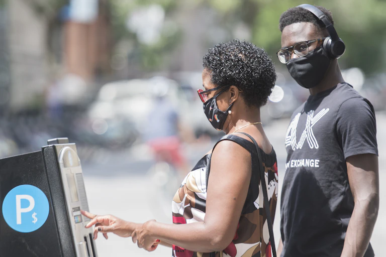 Two people wear face masks as they pay for parking