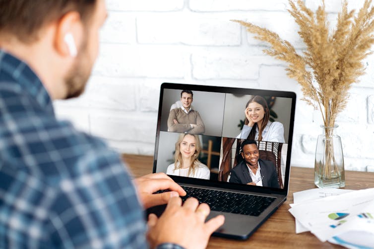 A man on his laptop in a video hookup with work colleagues.