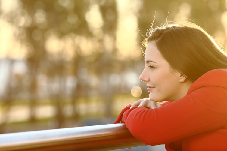 Woman smiling slightly looking into a golden sky.