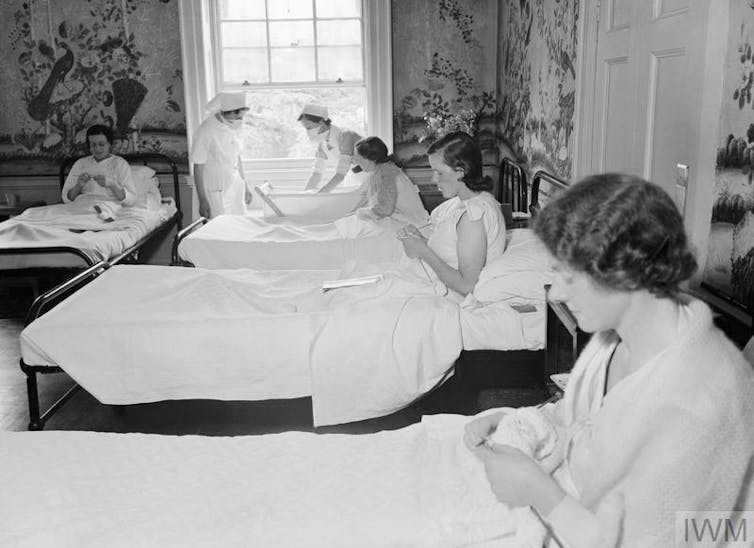 Historical image showing new mothers knitting in bed.