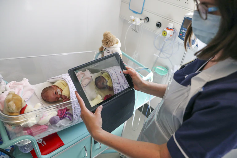 A nurse makes a video of a newborn baby in the maternity ward at Frimley Park Hospital in Surrey to send the parents as visiting hours are restricted because of the pandemic.