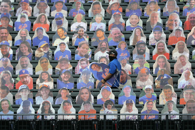 An employee of the New York Mets baseball team carries a cardboard cutout of a fan that will be placed in the empty stands.