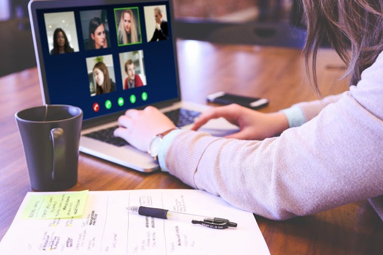 A woman with a laptop participates in a video conference meeting