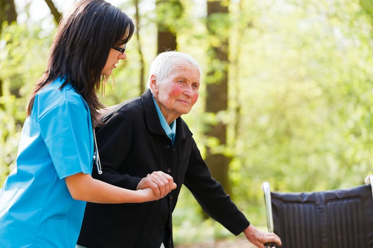 An elderly person is assisted by a carer.