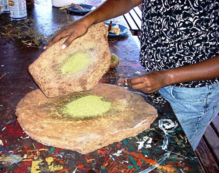 An indigenous person grinding native grain.