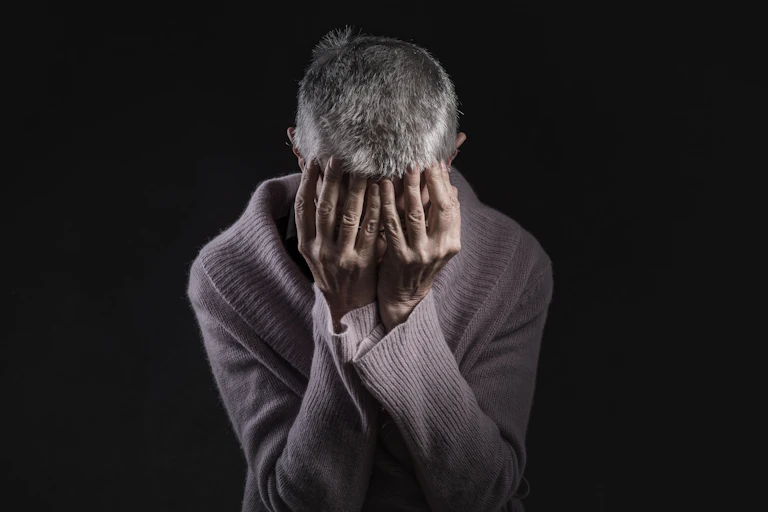 Despairing grey-haired women holds her head in her hands