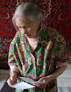 Older woman looks at her rent payment notices.