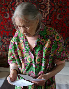 Older woman looks at her rent payment notices.
