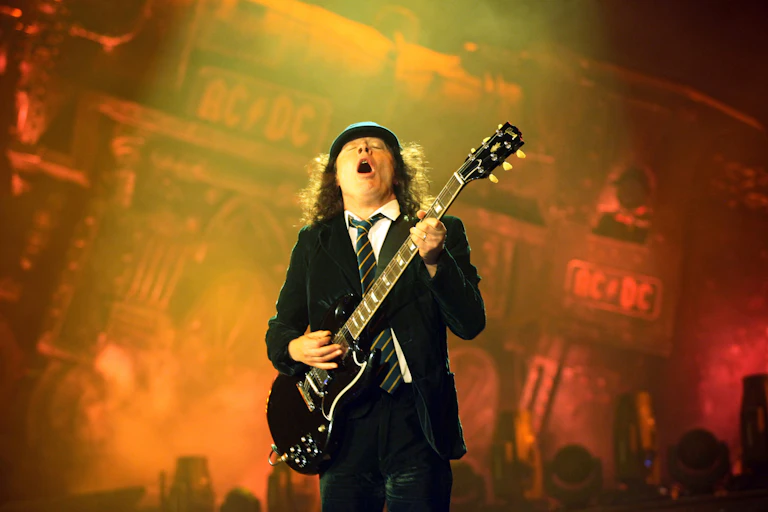AC/DC Andy Young playing guitar in school uniform.