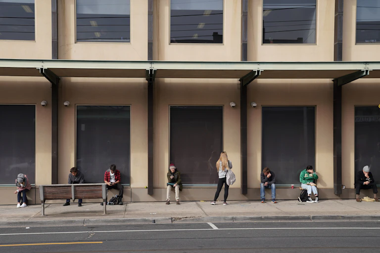 People sitting in a socially-distanced line outside a building