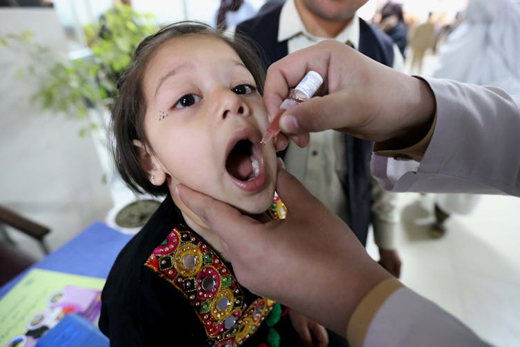 A health worker administers polio vaccine to a girl in Peshawar, Pakistan