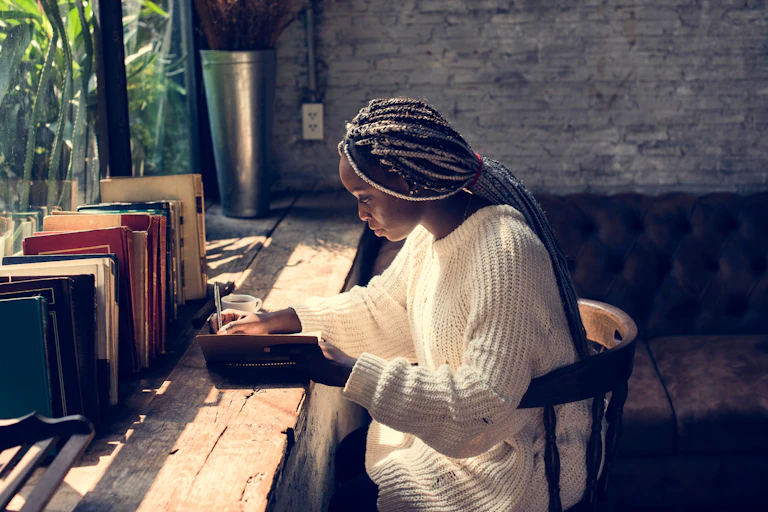 Woman writing in notebook at desk.